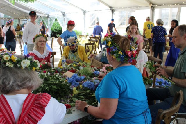 Women make flower crowns for people to wear at the midsummer festival.