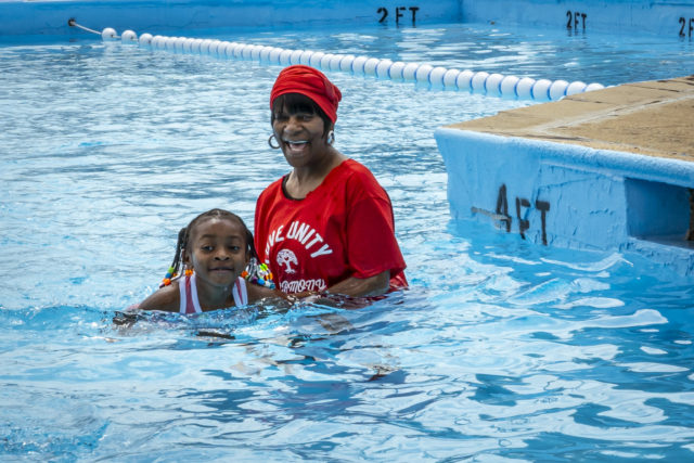An African-American woman helps a little girl swim in a Philadelphia Public Pool on June 17, 2024.