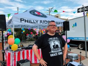 Peabody Award-winning radio host and producer at WXPN, DJ Robert Drake will emcee and spin tunes all day for everyone at the Philly AIDS Thrift block party. The DJ is standing in front of a Philly AIDS Thrift vendor tent. 